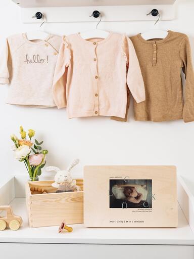 Baby-Erinnerungsbox befüllt mit Andenken steht zusammen mit dem personalisierten Deckel auf einer Wickelkommode