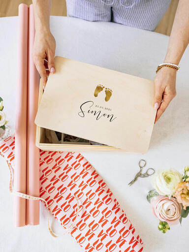 Frau verpackt eine personalisierte Baby-Erinnerungsbox als Geschenk