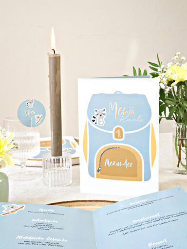 Menükarte für die Einschulungsfeier mit niedlichem Schulranzen-Design auf der dekorierten Festtafel