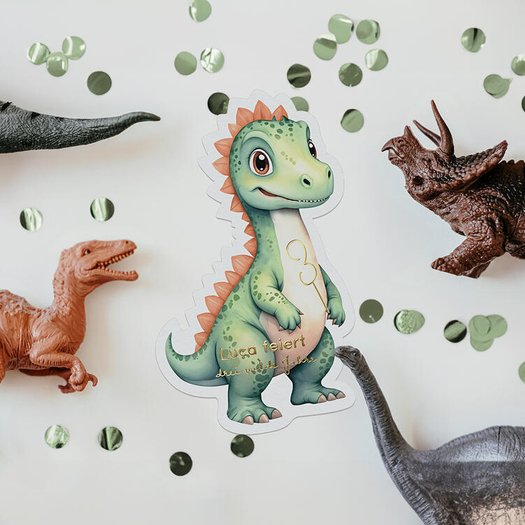 Einladungskarte der ‘Der Dino ist los’-Kollektion neben Tierfiguren und Konfetti